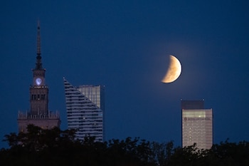 La luna llena, también conocida como la Luna del Esturión, se ocultó tras los rascacielos de Varsovia durante un eclipse lunar parcial, el 28 de agosto de 2026 (Sergei Gapon/AFP)