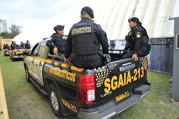 Agentes de SGAIA sentados sobre una camioneta pickup negra de su unidad con distintivos amarillos. Se ven más vehículos y personal policial en el fondo