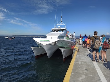 Varias personas esperan para embarcar en un barco de la naviera Mar de Ons.