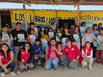 Un grupo diverso de jóvenes y adultos sonríe y posa para la foto, algunos de rodillas, sosteniendo certificados con la leyenda 'AL EMPLEO' frente a una pared amarilla con texto
