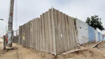 Vista exterior de la Institución Educativa Inca Pachacútec 6037. Se observan muros prefabricados y de ladrillo dañados, tierra removida en el suelo y un poste de luz