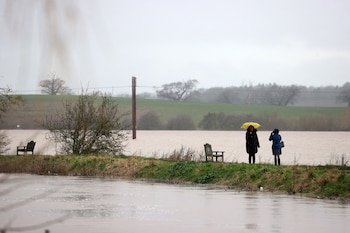 Unos peatones caminan por la orilla del río Avon (izda.) y el río Severn (dcha.), inundados, en Tewkesbury, al oeste de Inglaterra, el 3 de enero de 2024, tras la tormenta Henk, que trajo fuertes vientos y lluvias torrenciales a gran parte del país. Cientos de advertencias de inundaciones estaban en vigor en el Reino Unido el miércoles, después de que fuertes vientos y lluvias azotaran gran parte del país, afectando a los viajes y cortando el suministro eléctrico. (Foto de ADRIAN DENNIS / AFP)
