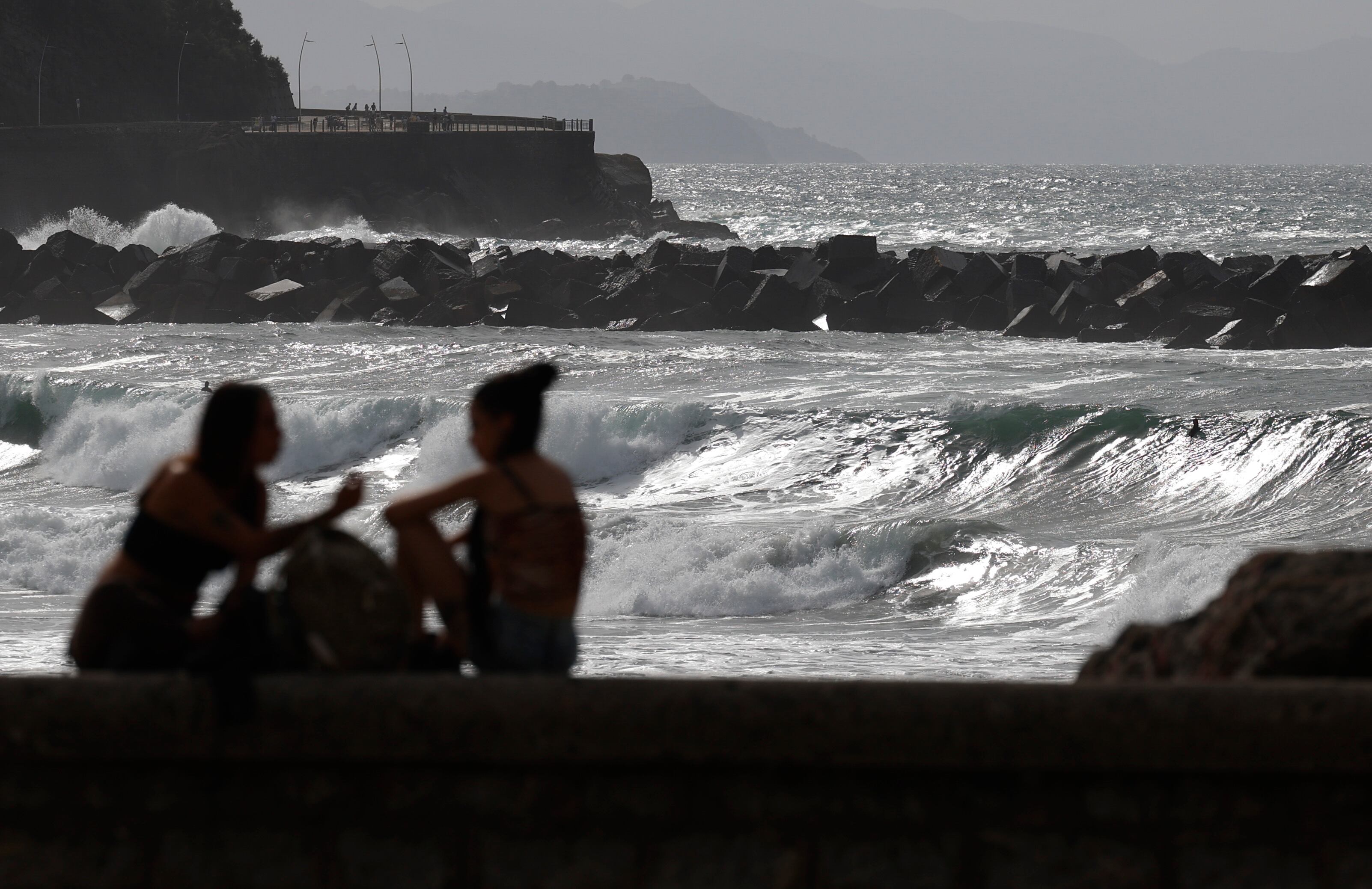 Unas jóvenes conversan junto a la playa dela Zurriola de San Sebastián, a 2 de septiembre de 2025. (EFE/Juan Herrero)