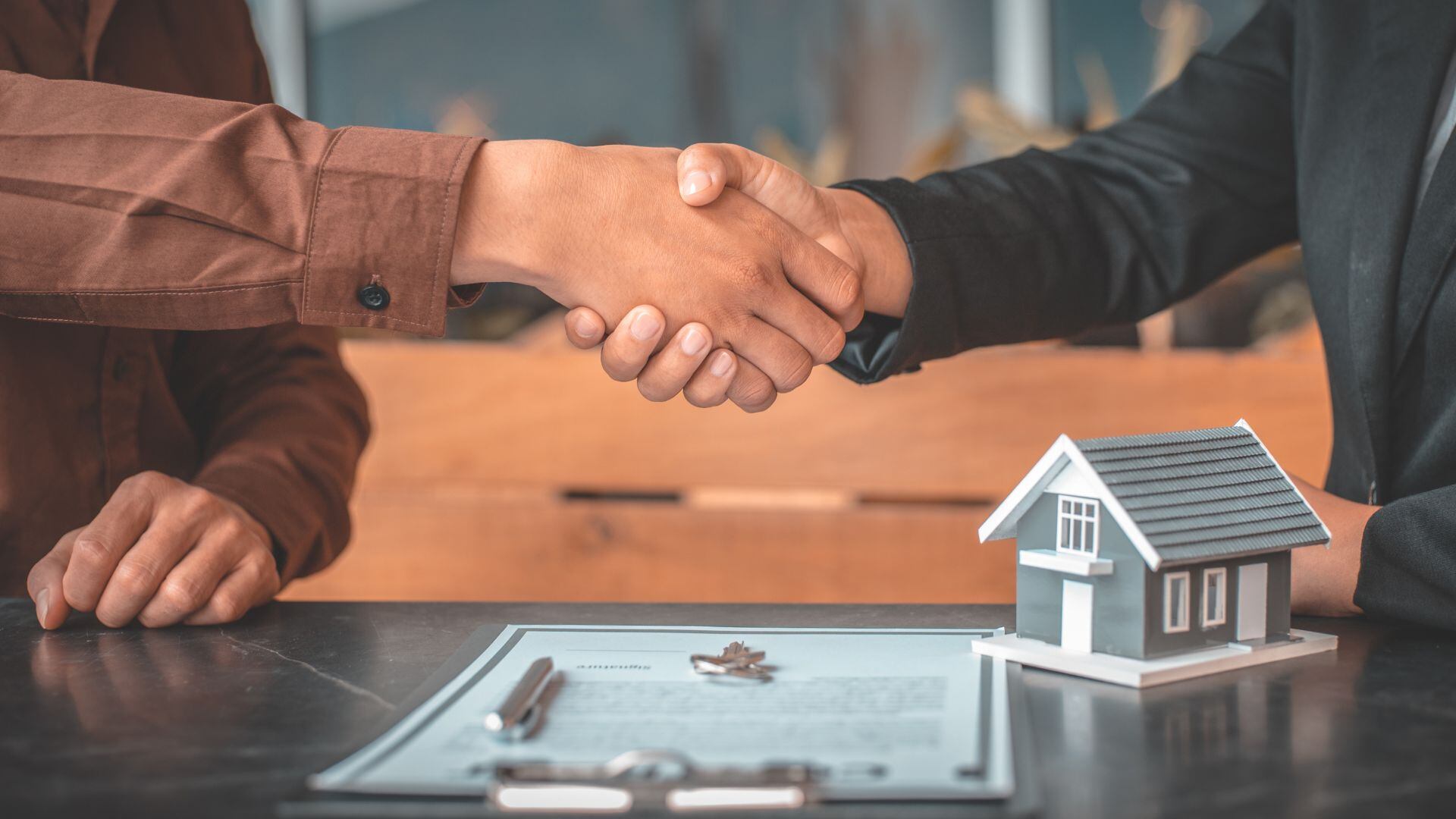 El antiguo y el nuevo propietario de una vivienda se estrechan la mano durante la transacción de compraventa (Canva)
