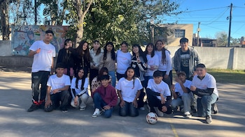 Grupo de dieciséis jóvenes y adolescentes posa al aire libre. La mayoría viste camisetas blancas con el logo 'cimientos'. Al fondo, un mural y árboles