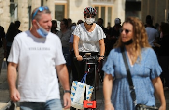 Personas con mascarillas pasan frente