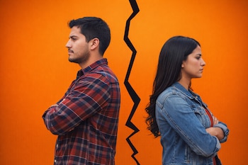 Un hombre y una mujer, ambos mexicanos, de perfil, espalda con espalda y brazos cruzados, separados por una grieta negra vertical sobre un fondo azul vibrante.
