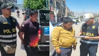 Agentes de policía con chalecos identificatorios custodian a dos hombres detenidos en una calle junto a camionetas