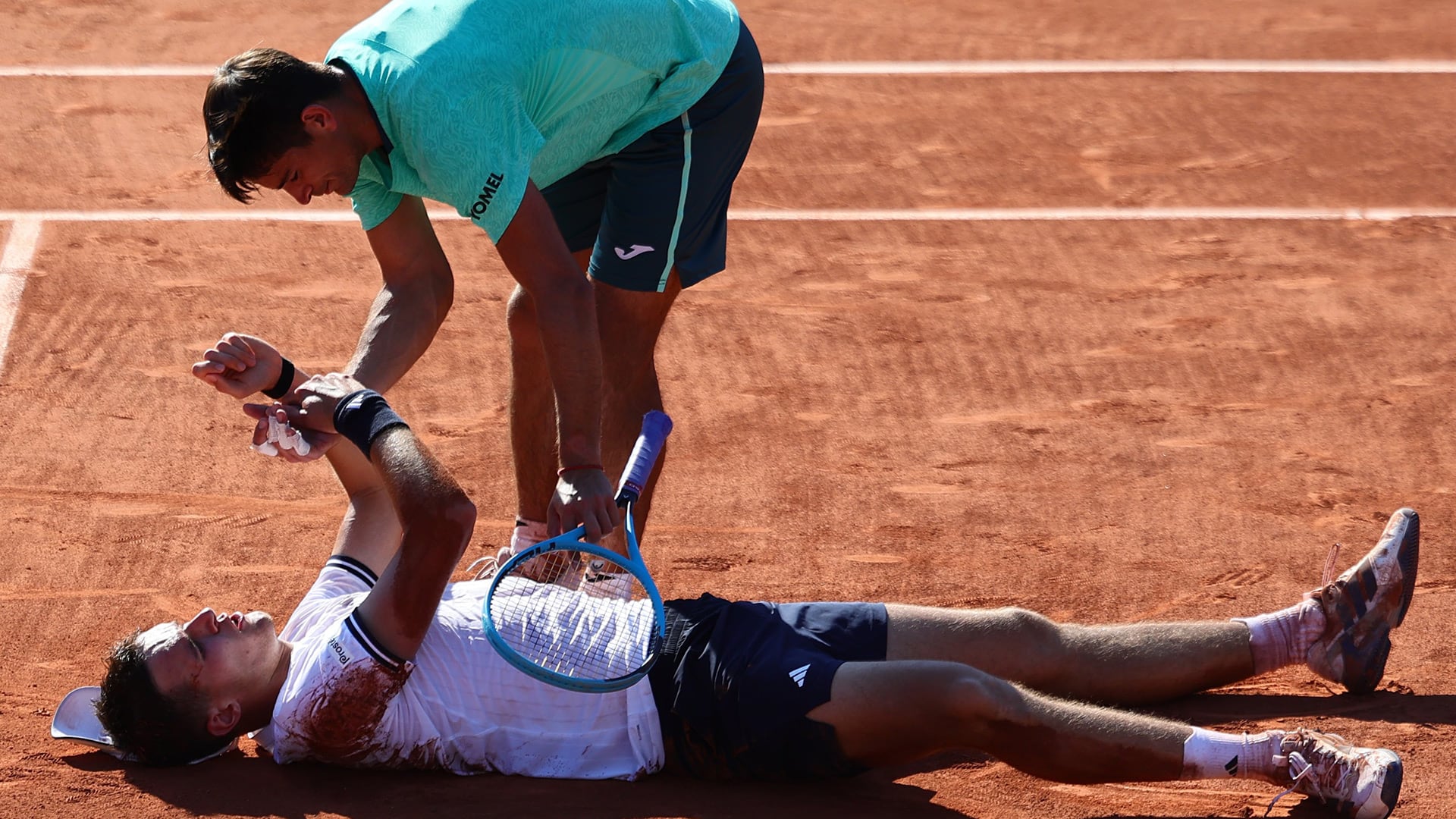 Mariano Navone saluda a Jakub Mensik, que quedó tendido en el suelo tras el partido (Fuente: X / @rolandgarros)