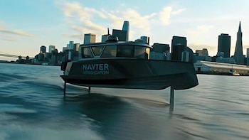 Un barco oscuro con la palabra 'NAVTER' en el costado se eleva sobre el agua impulsado por hidroalas, con una silueta urbana y un puente al fondo
