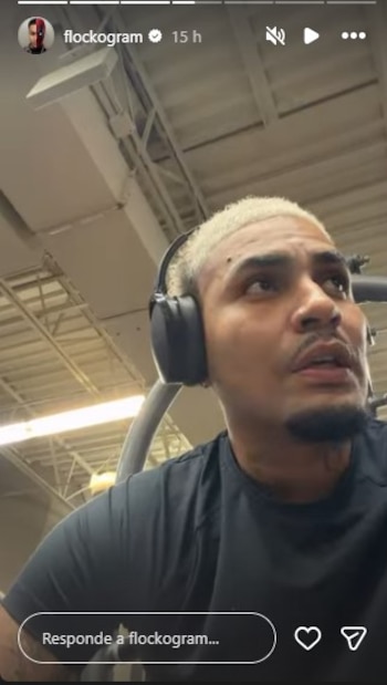 Youna, un hombre con cabello rubio decolorado y auriculares negros, se encuentra en un gimnasio, mirando hacia arriba con expresión concentrada