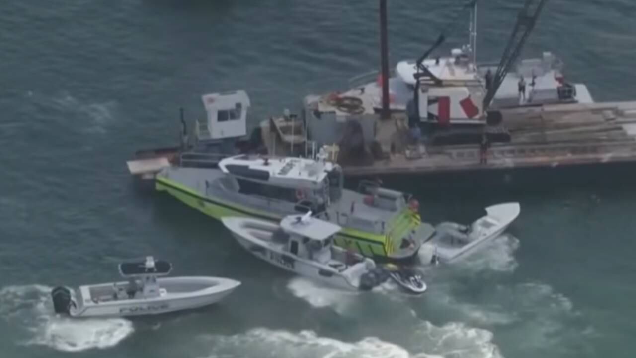 El catamarán quedó atrapado bajo la barcaza tras la colisión, provocando la muerte de tres menores que participaban en un campamento de vela del Miami Youth Sailing Foundation. (Capturas de video)