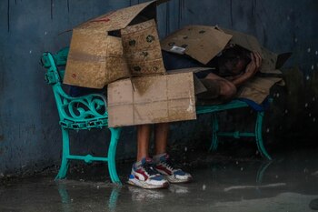 Dos personas se protegen de la lluvia y el viento con cartones en una parada de autobús durante el paso del huracán Rafael por La Habana, Cuba (AP Foto/Ramón Espinosa)