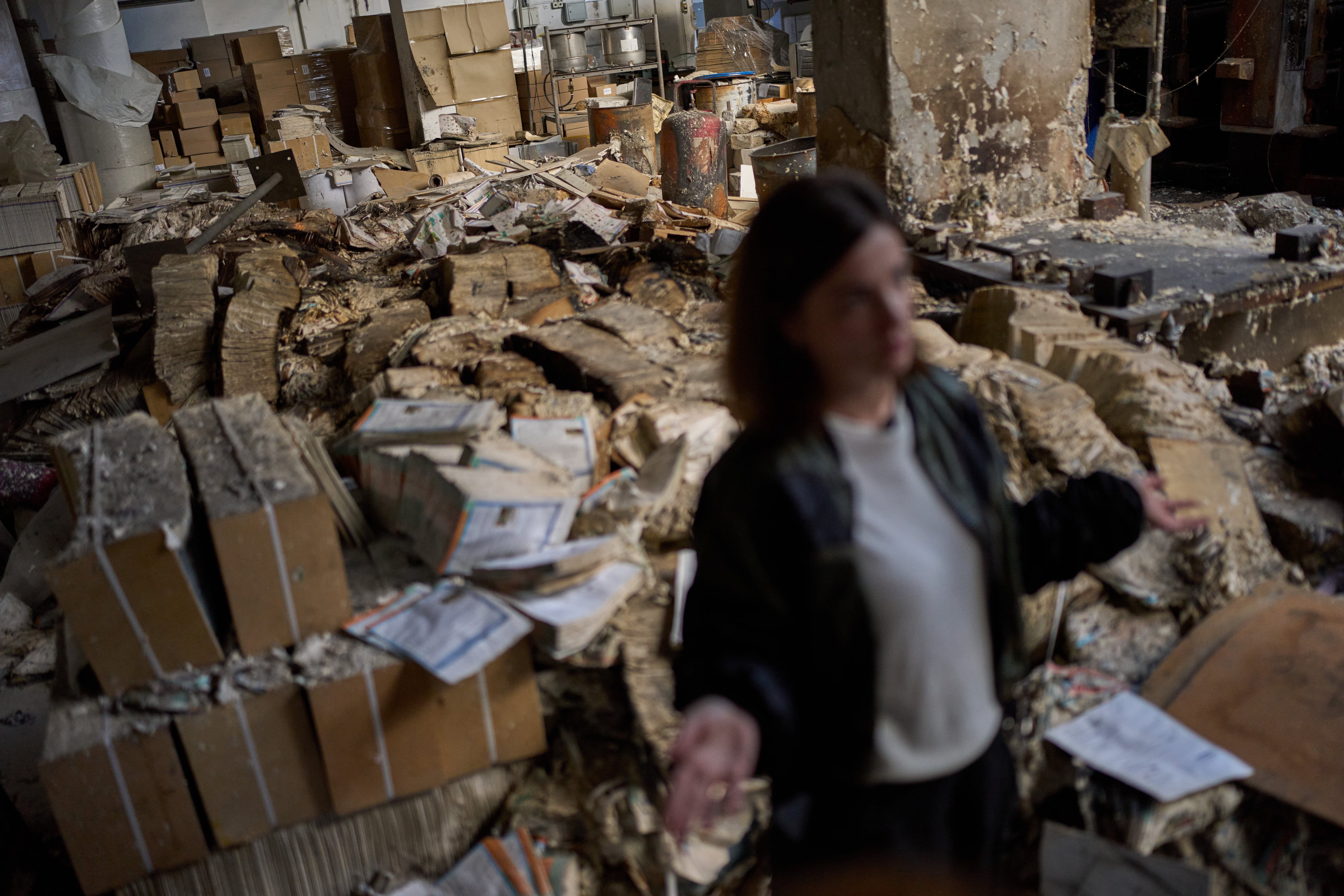 Viktoria Haidai, directora comercial de la imprenta Konvi, concede una entrevista junto a libros quemados en la imprenta destruida tras el impacto de un misil ruso en Kiev, Ucrania, el 7 de septiembre de 2026. (Foto AP/Francisco Seco, archivo)