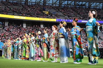 Performers in kimonos stand on