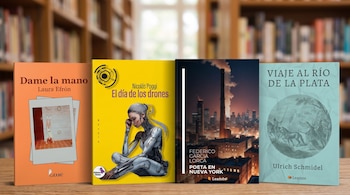 Cuatro libros impresos están apoyados verticalmente sobre una mesa de madera con estantes de libros desenfocados al fondo.