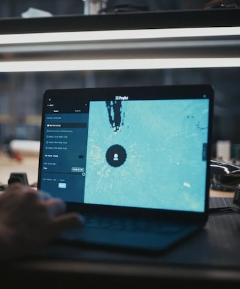 Una mano teclea en un portátil oscuro sobre un escritorio, cuya pantalla muestra un mapa de radar azul claro con un círculo central y datos de reflectividad