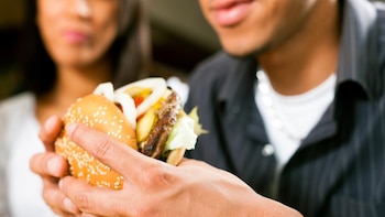Un hombre comiendo una hamburguesa.