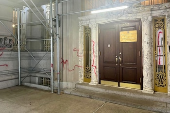 Fachada del Consulado de Polonia en Nueva York con puertas de madera y un letrero dorado, visiblemente marcada con pintura roja y andamios al lado