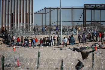 Migrantes formados después de ser detenidos por las autoridades migratorias de Estados Unidos en el muro fronterizo, el miércoles 27 de diciembre de 2023, en una imagen captada desde Ciudad Juárez, México. (AP Foto/Christian Chavez)