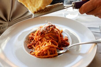 A person grates parmesan cheese