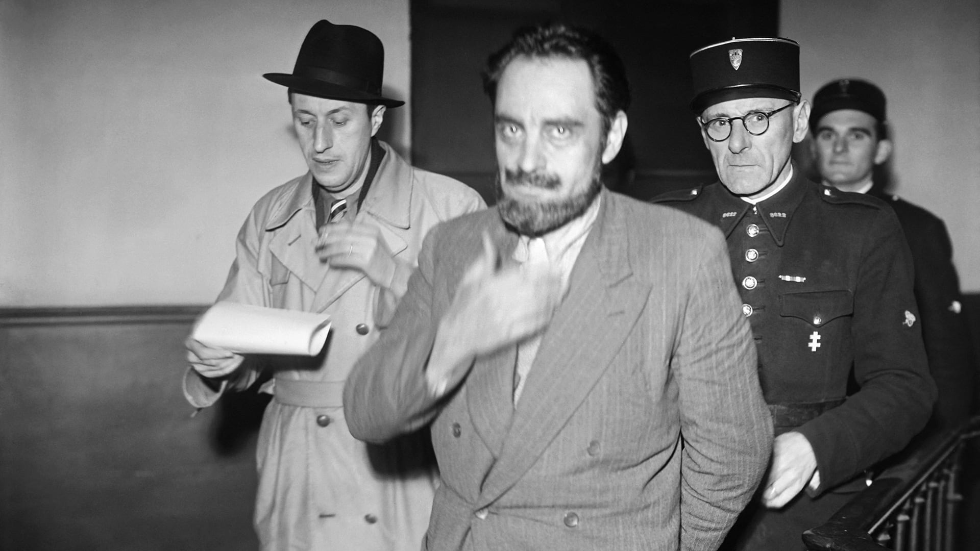 El doctor Marcel Petiot conducido por los pasillos del número 36 del quai des Orfèvres, sede de la Policía Judicial parisina, poco después de su arresto el 31 de octubre de 1944 AFP (The Grosby Group)