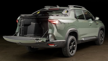 Camioneta verde oliva con la caja de carga abierta, tracción cuatro por cuatro y detalles negros sobre un fondo oscuro