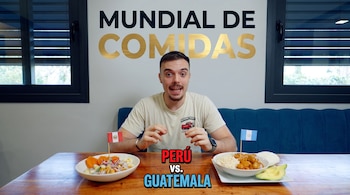 Ibai Llanos sentado ante una mesa con un plato de cebiche con la bandera de Perú y un plato con la bandera de Guatemala.