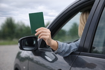 Una mujer muestra un pasaporte por la ventanilla del coche.