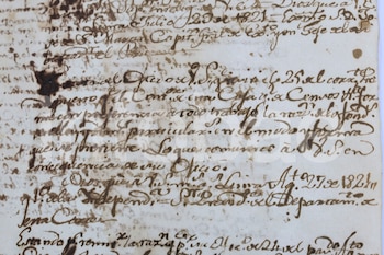Primer plano de un documento antiguo con escritura manuscrita en tinta marrón sobre papel blanquecino, con manchas de humedad y decoloración