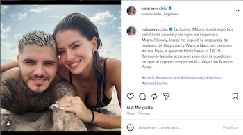 Un hombre con tatuajes en los brazos y el torso y una mujer sonríen recostados sobre la arena en una playa