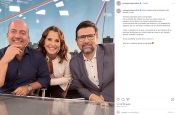 Tres conductores de televisión sonríen frente a un escritorio de vidrio dentro de un estudio con ventanales