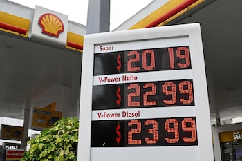 Un cartel digital de precios en una estación Shell muestra 'Super $20.19', 'V-Power Nafta $22.99' y 'V-Power Diesel $23.99' bajo un techo amarillo y rojo