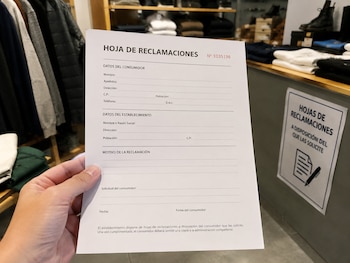Un cliente de una tienda de ropa cubriendo una hoja de reclamaciones (Imagen Ilustrativa Infobae)