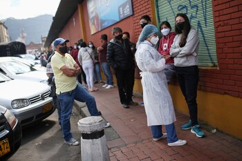 Personas con mascarillas hacen fila