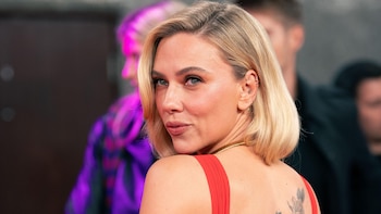 Retrato de Scarlett Johansson luciendo un vestido rojo y cabello rubio corto mientras mira sobre su hombro