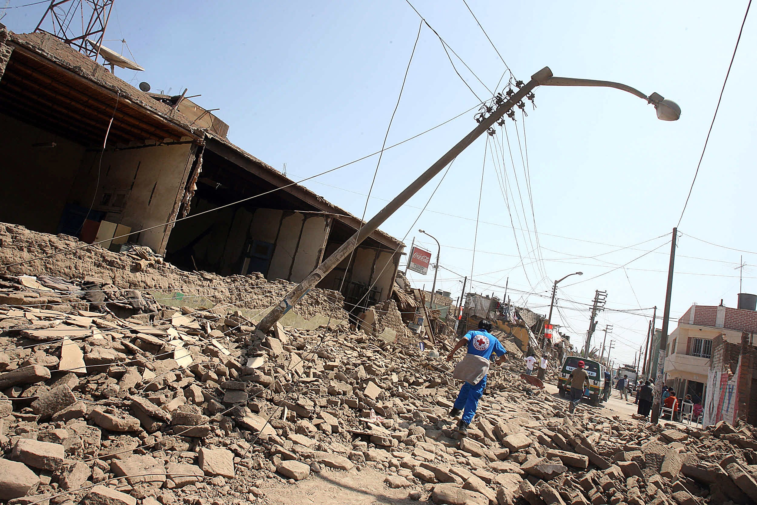 Un miembro de la Cruz Roja Peruana corre por una calle devastada en Pisco, a más de 300 km al sur de Lima, el 16 de agosto de 2007. Las autoridades peruanas se esforzaron el jueves por llegar a las víctimas aisladas en la costa sur del país tras el devastador terremoto que sacudió la región la víspera, dejando más de 500 muertos y 1600 heridos. FOTO AFP/Jaime RAZURI (Foto de JAIME RAZURI / AFP)