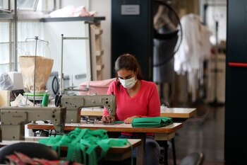 Una mujer cose mascarillas faciales