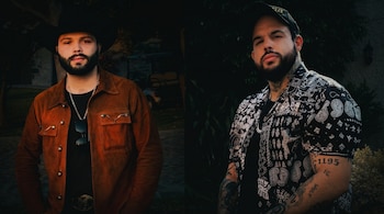 Dos hombres posan lado a lado. Uno lleva sombrero vaquero, chaqueta marrón, camiseta negra, cadena y gafas; el otro, gorra, camisa estampada y tatuajes visibles.
