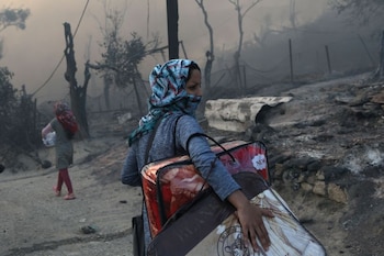 Dos refugiadas cargan con sus pertenecientes mientras huyen del incendio desatado en el campamento de Moria, en la isla griega de Lesbos. 9 de septiembre de 2020. REUTERS/Elias Marcou TPX IMAGES OF THE DAY