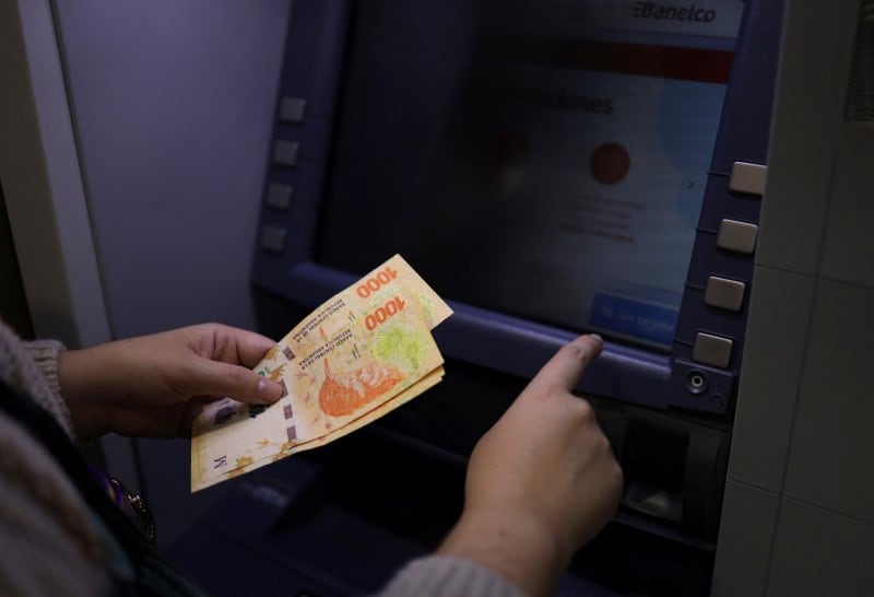 Foto de archivo: - Una mujer retira pesos argentinos de un cajero automático en Buenos Aires REUTERS/Cristina Sille