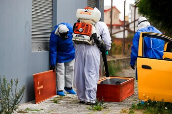 Miembros de la policía de Ecuador, protegidos con trajes de seguridad, fueron registrados este miércoles, al hacer el levantamiento del cuerpo de un anciano que murió en un taxi con sospecha de COVID-19, en Quito (Ecuador). EFE/José Jácome