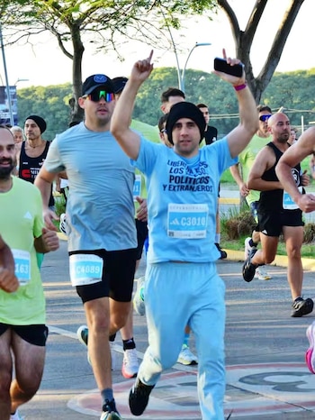 Primer plano de un torso con camiseta azul claro y texto negro 'LIBEREN A TODOS LOS PRESOS POLÍTICOS Y EXTRANJEROS'. Un dorsal 'SUPERNOVA 10K' es visible