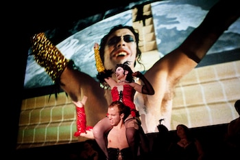 FILE — Performers engage with the audience as Tim Curry is displayed on screen during a midnight showing of “The Rocky Horror Picture Show” at the Chelsea Clearview Cinema in New York, Nov. 23, 2012. Curry, the British-born actor whose gift for caricature and garish eccentricity informed a variety of performances on stage and screen, notably as the puerile Mozart in the original Broadway production of “Amadeus” and as the outlandish cross-dressing mad scientist in the midnight cult film “The Rocky Horror Picture Show,” died on Tuesday, Aug. 25, 2026. He was 80. (Julie Glassberg/The New York Times)