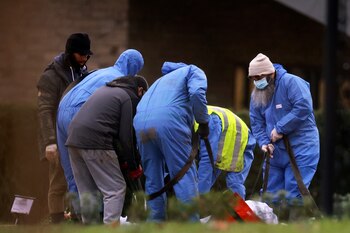 Trabajadores con trajes protectores entierran
