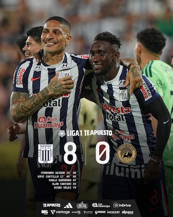 Dos jugadores de Alianza Lima, sonriendo y con camisetas a rayas azules y blancas, se abrazan en un campo de fútbol. Un marcador digital muestra "8-0"