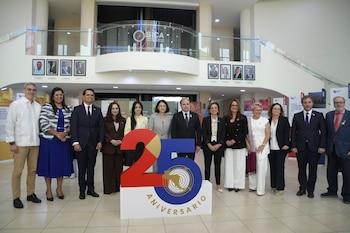 Catorce personas, hombres y mujeres, posan frente a un cartel de "25 Aniversario" en un vestíbulo moderno. El logo de SICA es visible en el balcón superior