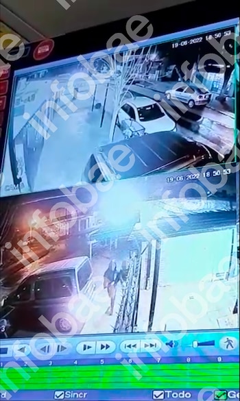 Un monitor de seguridad muestra dos grabaciones: la superior con vehículos en una calle, la inferior con una persona junto a un coche y controles de reproducción