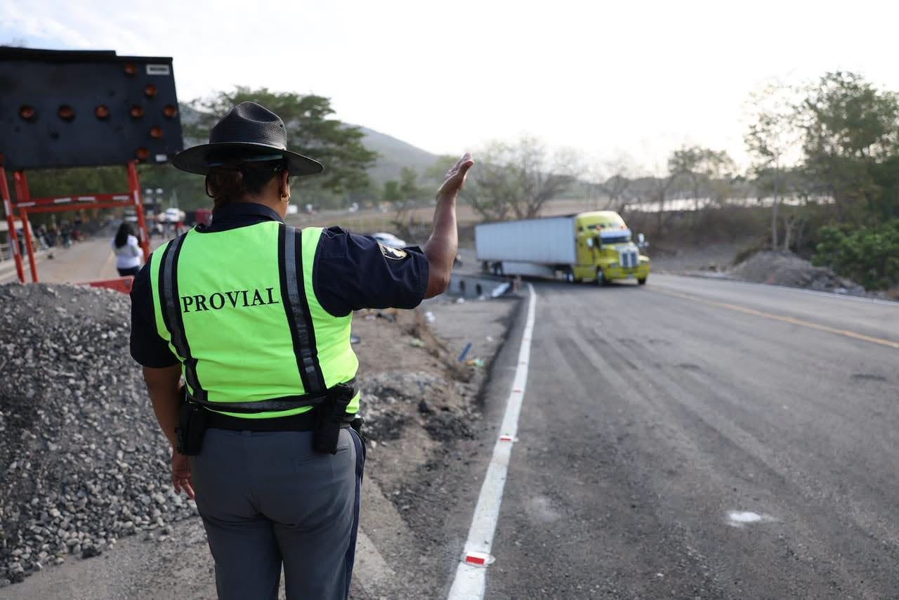Una agente de Provial dirige el tráfico de vehículos pesados junto a una zona de obras en una carretera. (Ministerio de Comunicaciones, Infraestructura y Vivienda)