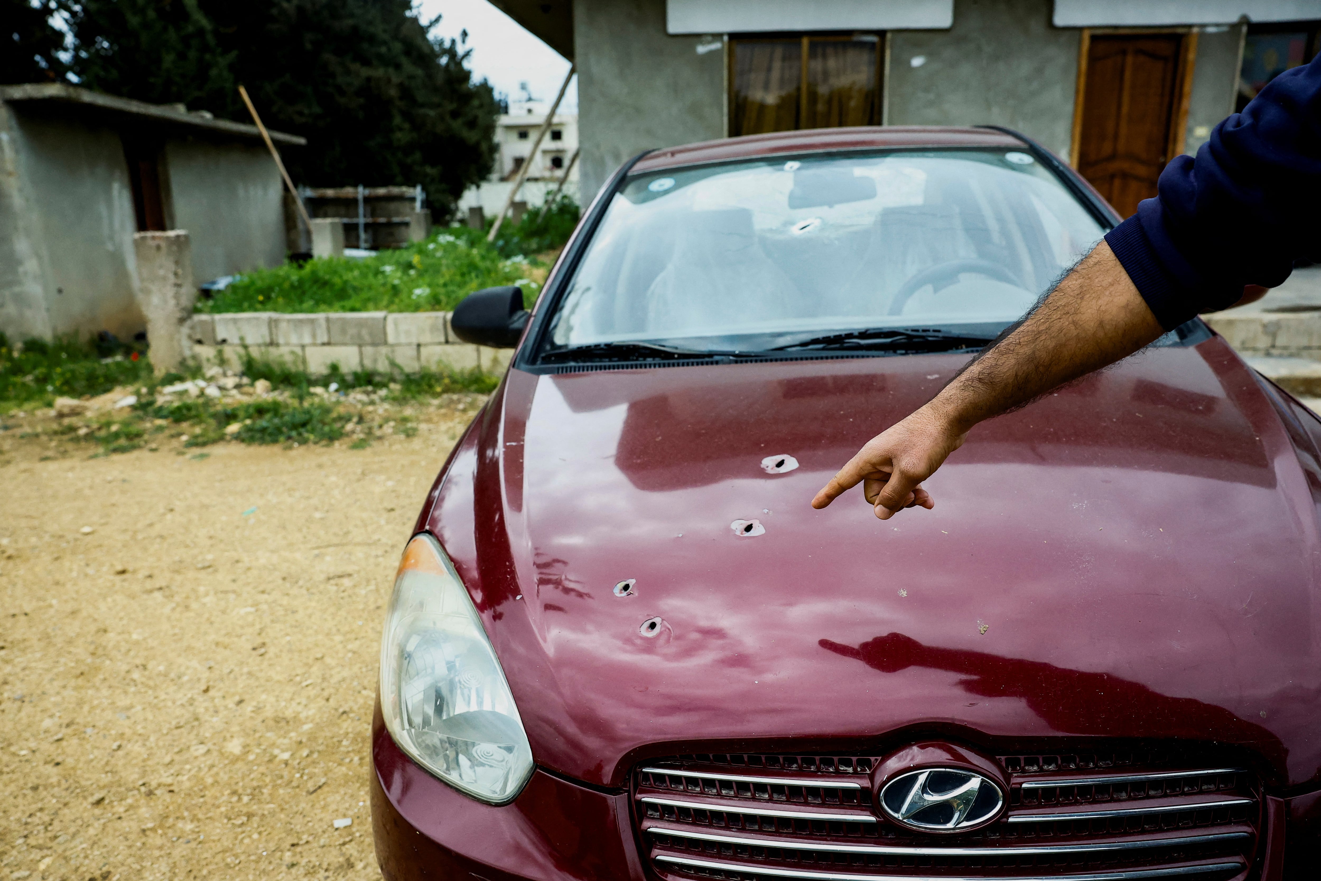 Un hombre señala los agujeros de bala en su coche en Al-Qabu, una de las ciudades más afectadas por la violencia. Muchos alauitas dicen que siguen teniendo miedo hasta el día de hoy ( REUTERS/Stringer)